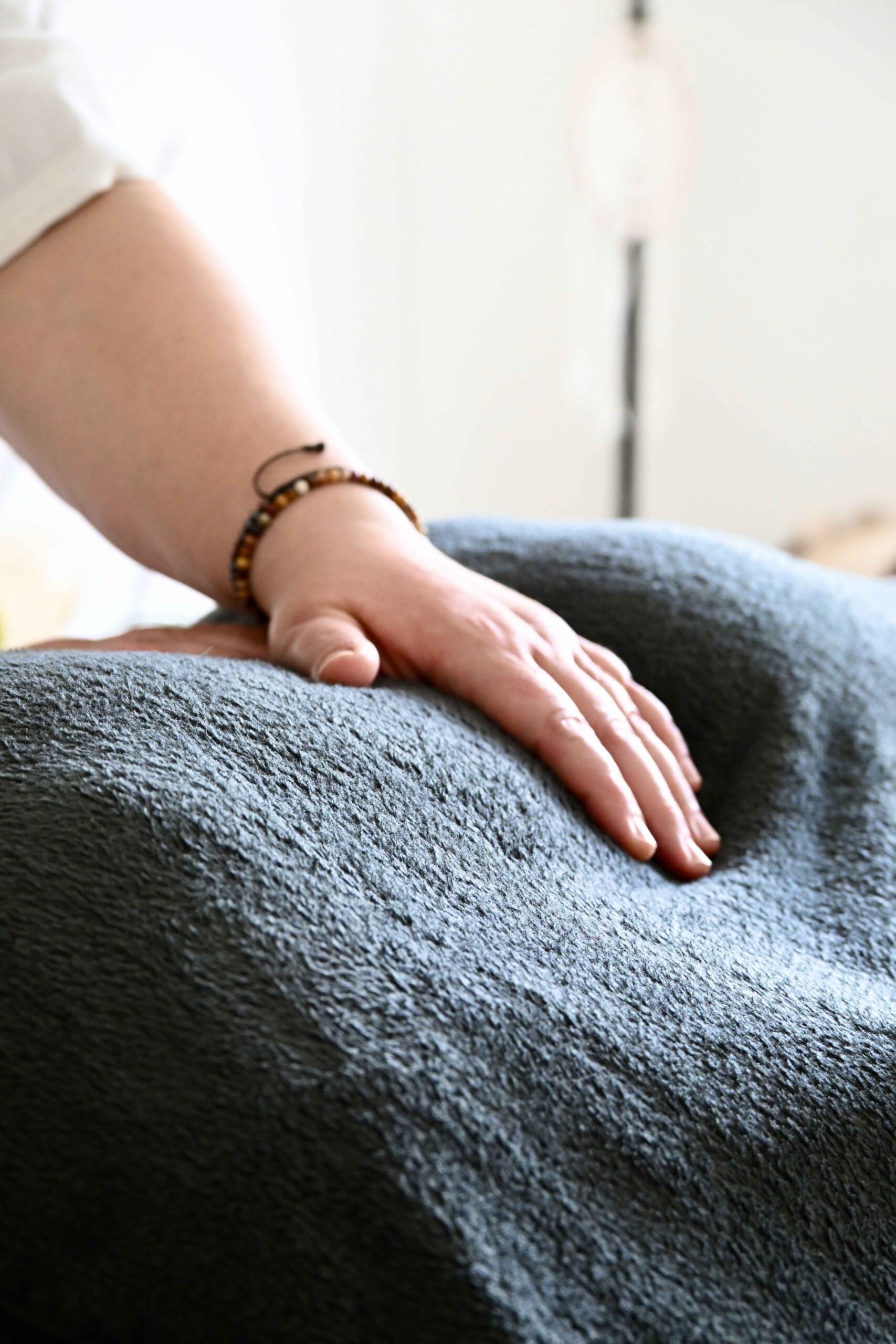 Main sur un corps allongé sous une table de massage lors d'une séance de Reiki
